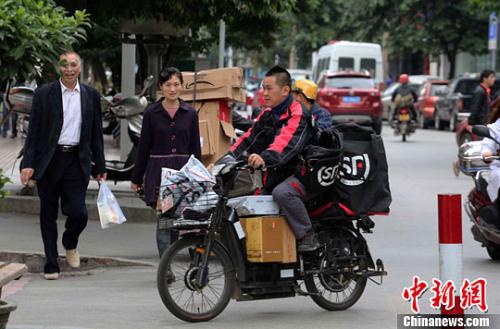 一名快遞公司送貨員正騎著滿(mǎn)載快件的電單車(chē)在市區(qū)內(nèi)送貨。李俊鋒 攝