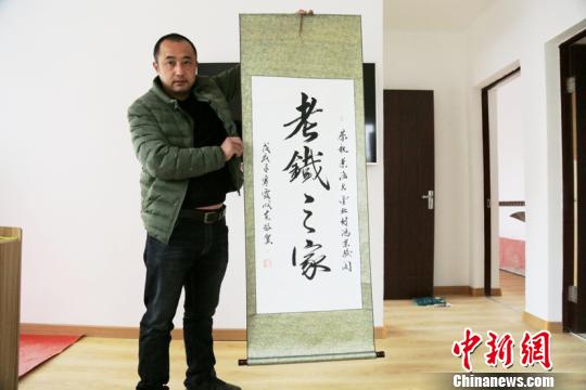 阿木爾林業(yè)局網(wǎng)紅劉老四展示粉絲贈送的“老鐵之家”書法作品。(王力攝)